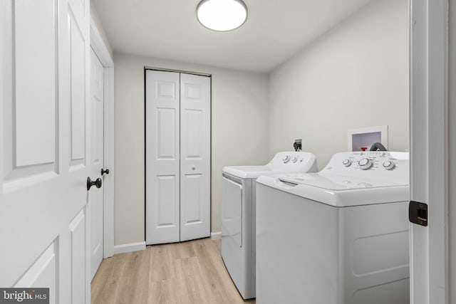 laundry room featuring washer and clothes dryer and light hardwood / wood-style flooring