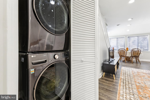 clothes washing area featuring hardwood / wood-style flooring and stacked washer and clothes dryer