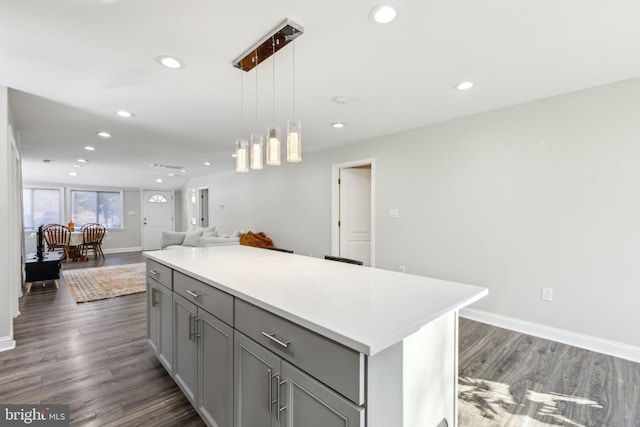 kitchen with pendant lighting, dark hardwood / wood-style flooring, a center island, and gray cabinetry