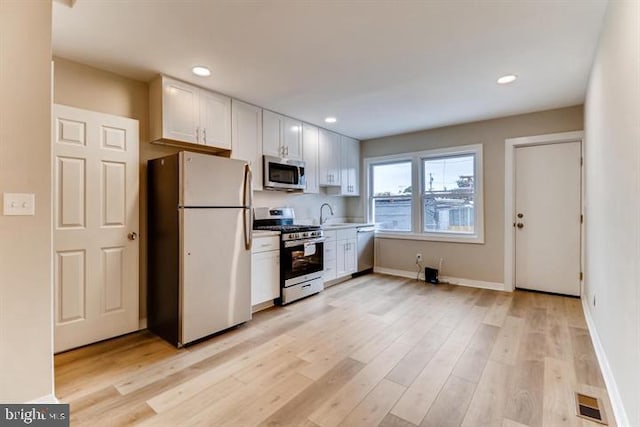 kitchen with white cabinetry, appliances with stainless steel finishes, sink, and light hardwood / wood-style flooring