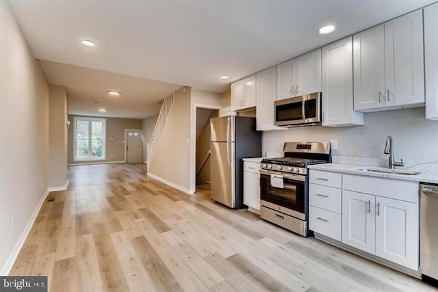 kitchen with white cabinetry, appliances with stainless steel finishes, sink, and light hardwood / wood-style flooring