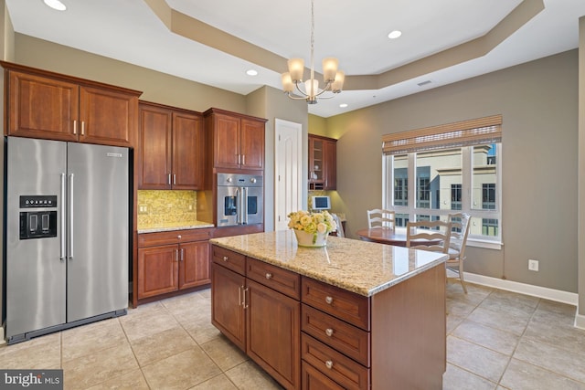 kitchen featuring stainless steel appliances, light stone counters, a kitchen island, decorative backsplash, and decorative light fixtures