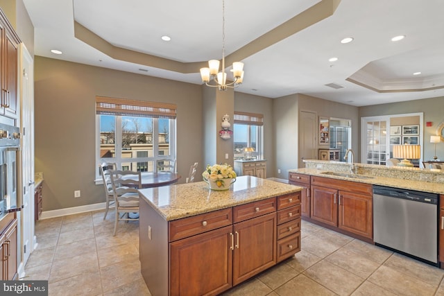 kitchen with sink, hanging light fixtures, stainless steel dishwasher, light stone counters, and a tray ceiling