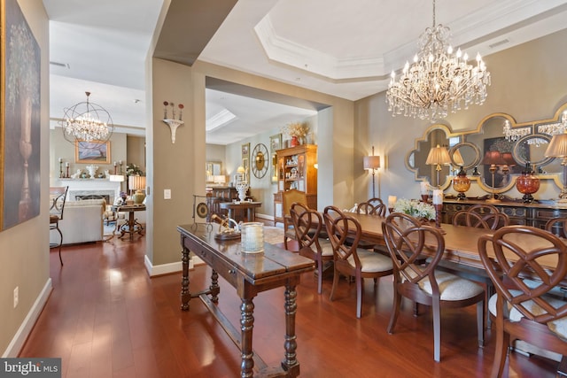 dining room with dark wood-type flooring, a tray ceiling, crown molding, and an inviting chandelier