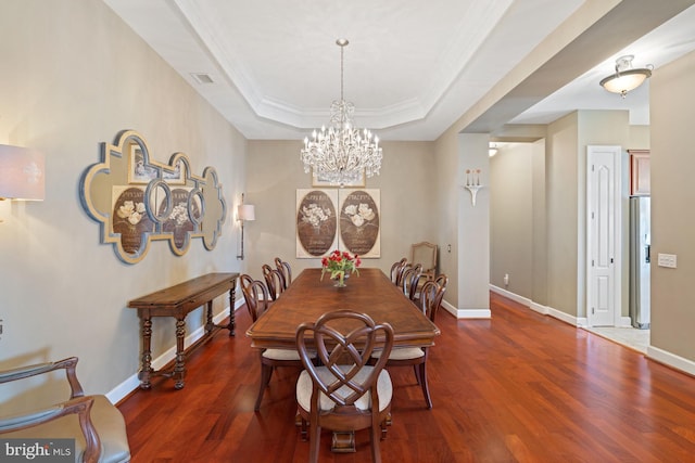 dining area featuring crown molding, an inviting chandelier, dark hardwood / wood-style flooring, and a tray ceiling