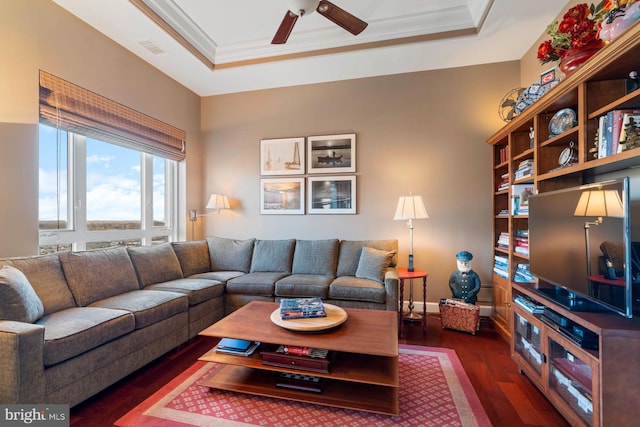 living room with dark hardwood / wood-style flooring, crown molding, a raised ceiling, and ceiling fan