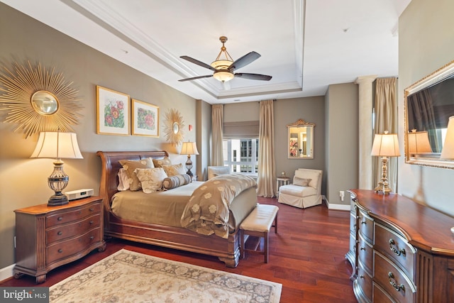 bedroom with ornamental molding, dark hardwood / wood-style floors, ceiling fan, and a tray ceiling