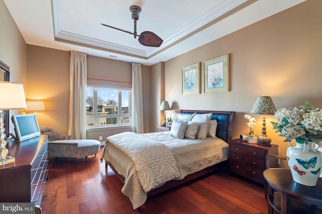 bedroom featuring crown molding, dark hardwood / wood-style flooring, and a raised ceiling