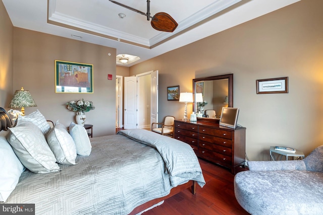 bedroom featuring dark wood-type flooring, ornamental molding, and a raised ceiling