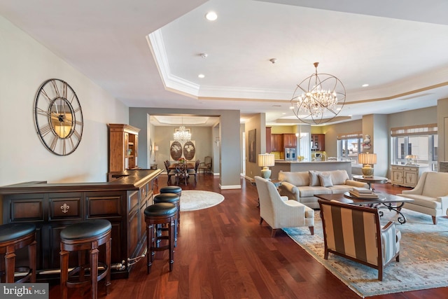 living room with an inviting chandelier, ornamental molding, dark hardwood / wood-style floors, and a raised ceiling