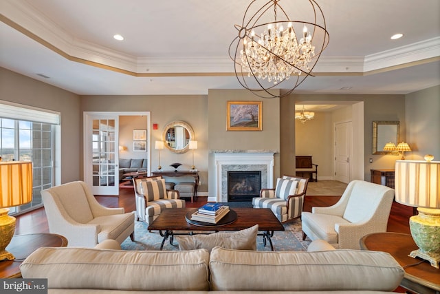 living room featuring a raised ceiling, crown molding, wood-type flooring, and a high end fireplace