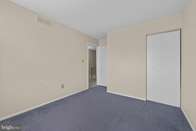 unfurnished bedroom with dark carpet and a closet