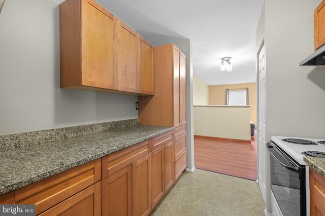 kitchen with ventilation hood, electric range oven, and dark stone countertops