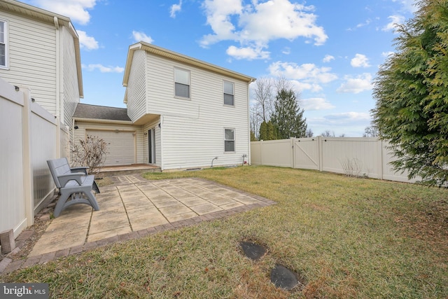 back of property featuring a garage, a patio, and a lawn