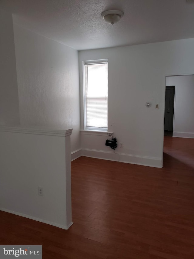 spare room with dark wood-type flooring and a textured ceiling