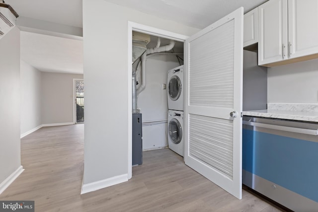 laundry room featuring light wood finished floors, stacked washer / dryer, and baseboards