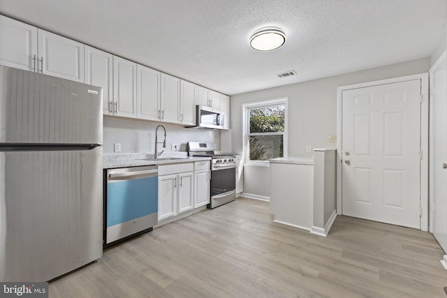 kitchen featuring white cabinets, visible vents, appliances with stainless steel finishes, and light countertops