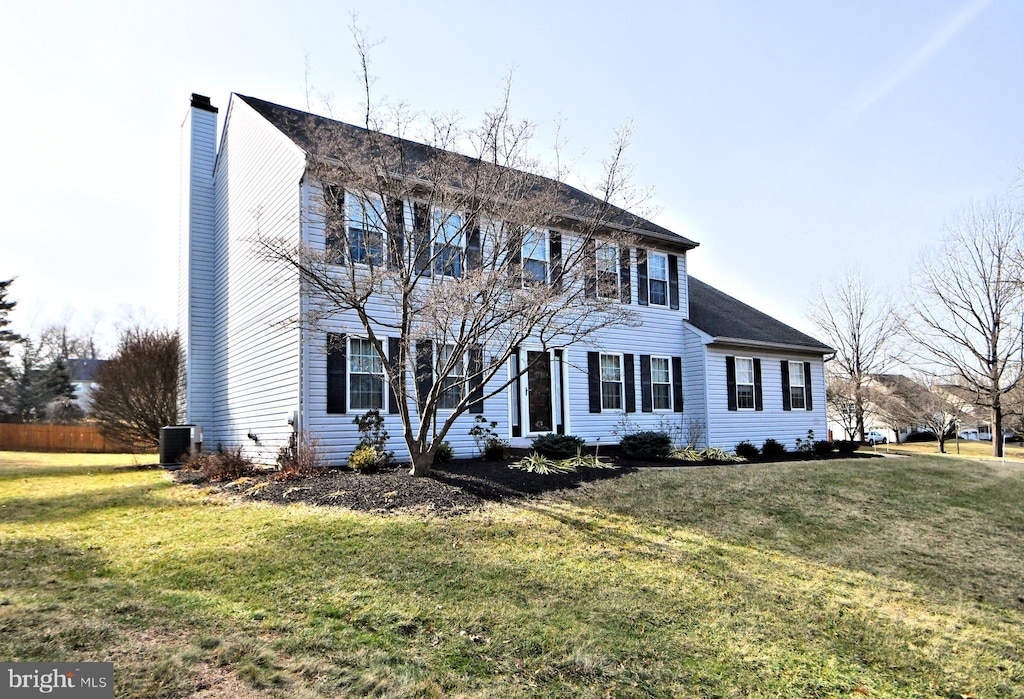 colonial inspired home featuring cooling unit and a front lawn