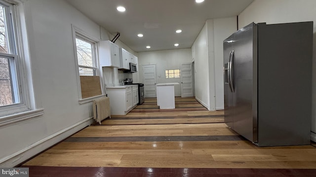 kitchen with radiator, white cabinetry, a baseboard radiator, dark hardwood / wood-style flooring, and stainless steel appliances