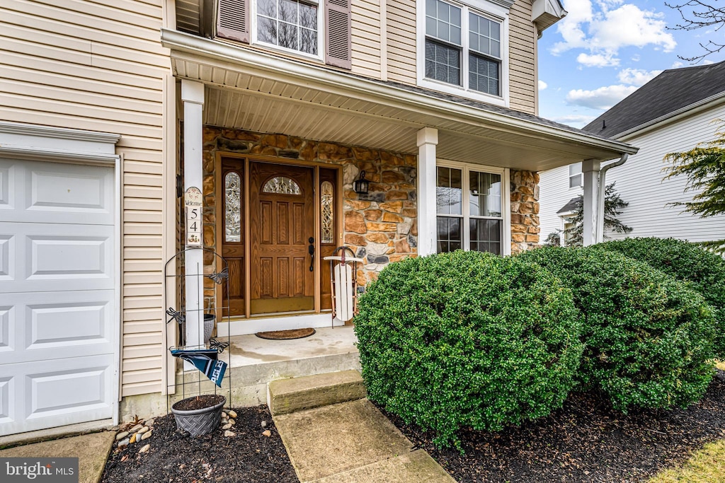 view of exterior entry with a porch and stone siding