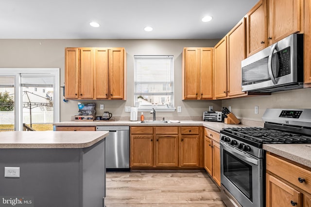 kitchen featuring appliances with stainless steel finishes, sink, and light wood-type flooring