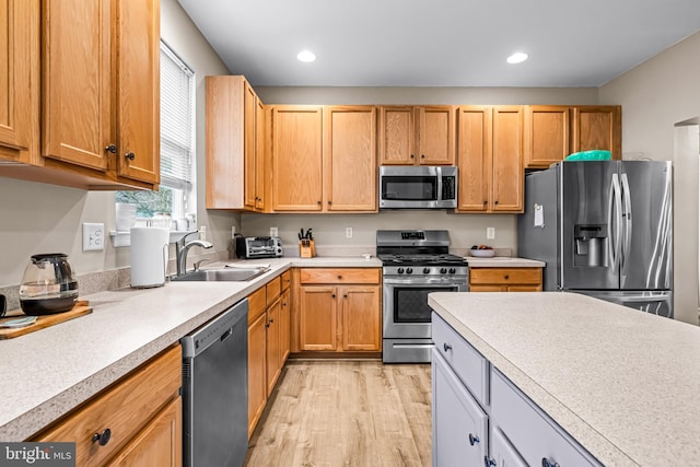 kitchen with stainless steel appliances, sink, and light hardwood / wood-style flooring