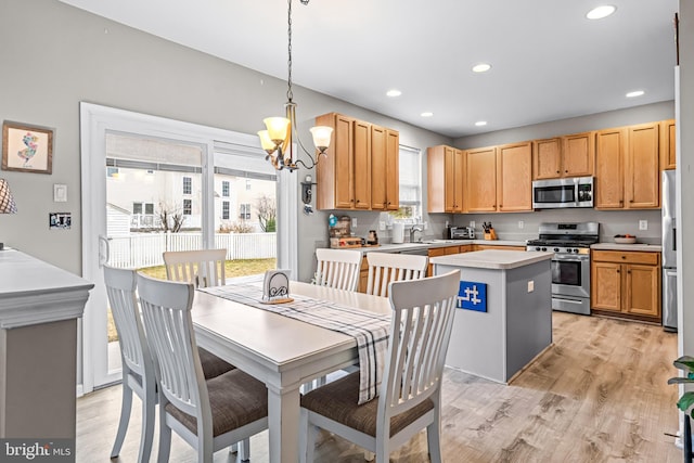 kitchen featuring pendant lighting, stainless steel appliances, a center island, and light hardwood / wood-style floors