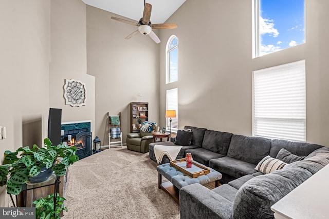 carpeted living room featuring ceiling fan, a high end fireplace, and a high ceiling