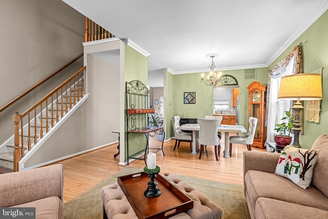 living room featuring crown molding, a chandelier, and light hardwood / wood-style floors