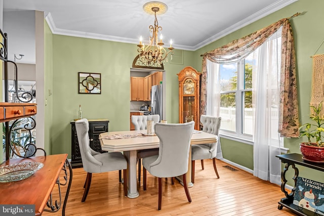 dining room featuring a notable chandelier, ornamental molding, and light wood-type flooring