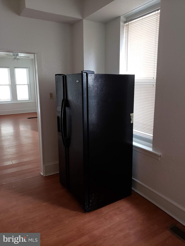 kitchen featuring black fridge with ice dispenser, wood-type flooring, and ceiling fan