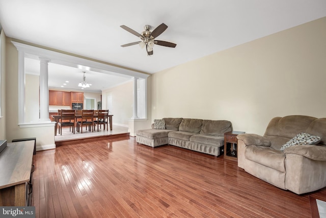 living room with hardwood / wood-style flooring, ceiling fan with notable chandelier, and ornate columns