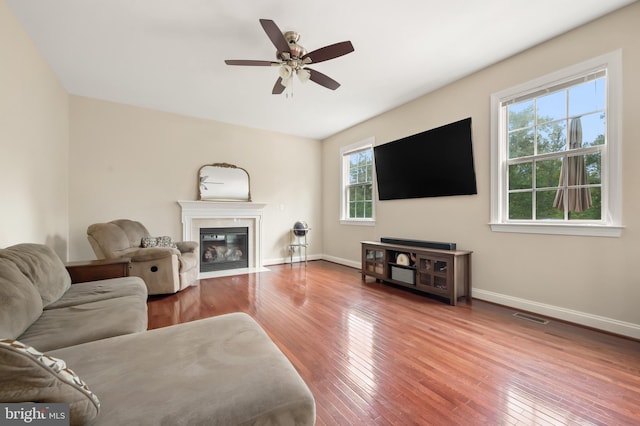 living room featuring ceiling fan, wood-type flooring, and a high end fireplace