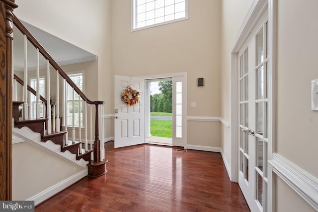 foyer featuring crown molding, dark hardwood / wood-style floors, a healthy amount of sunlight, and french doors