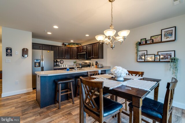 dining room featuring hardwood / wood-style flooring, sink, and an inviting chandelier