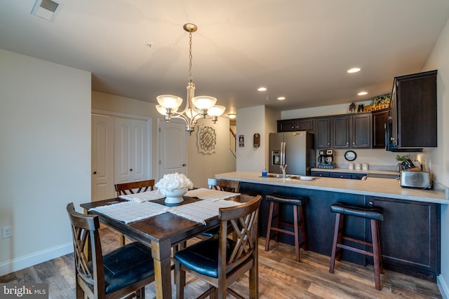 dining area featuring hardwood / wood-style flooring, an inviting chandelier, and sink