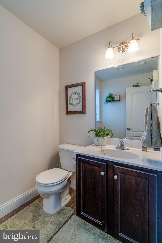 bathroom featuring vanity, wood-type flooring, and toilet