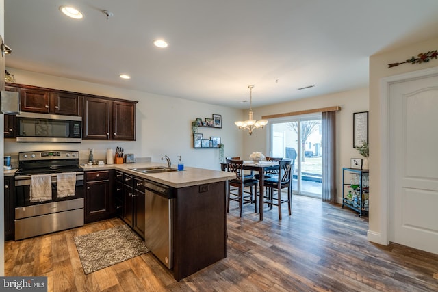 kitchen featuring sink, dark brown cabinets, hanging light fixtures, appliances with stainless steel finishes, and kitchen peninsula