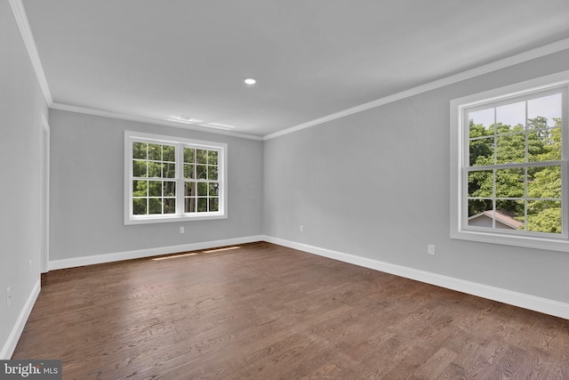 empty room with dark wood-style flooring, crown molding, and baseboards