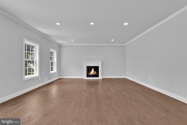 unfurnished living room with recessed lighting, wood finished floors, baseboards, ornamental molding, and a glass covered fireplace