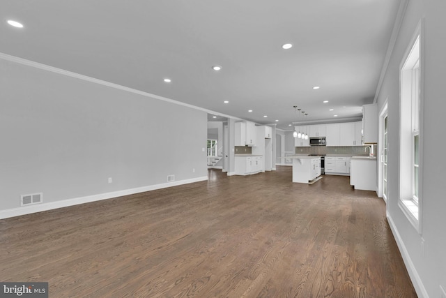 unfurnished living room featuring dark wood-style floors, baseboards, visible vents, and crown molding