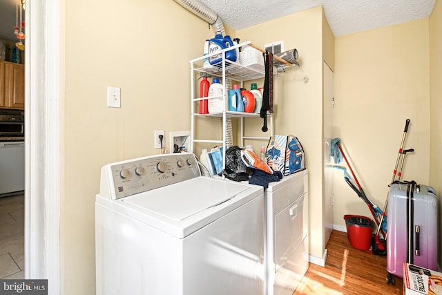 clothes washing area featuring hardwood / wood-style flooring, washer and dryer, and a textured ceiling