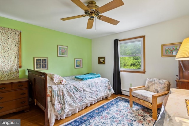 bedroom with hardwood / wood-style flooring, a baseboard radiator, and ceiling fan