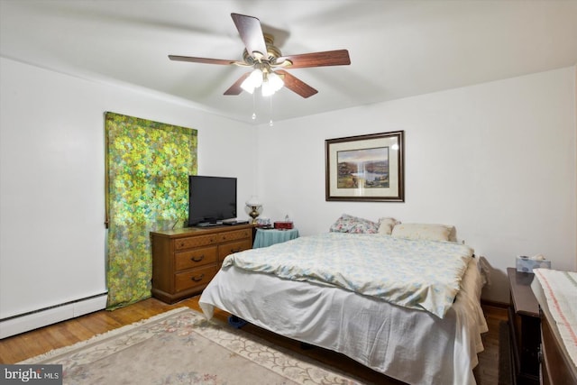 bedroom featuring ceiling fan, wood-type flooring, and a baseboard heating unit