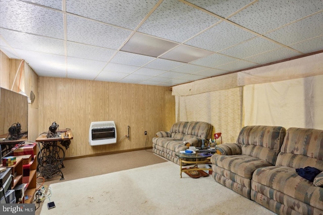 carpeted living room featuring heating unit, a drop ceiling, and wooden walls