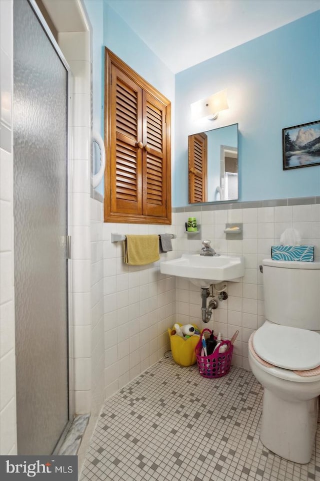 bathroom featuring sink, tile walls, walk in shower, toilet, and tile patterned floors