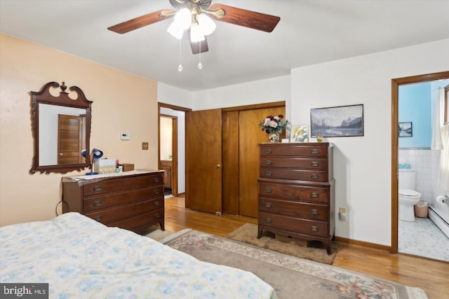 bedroom featuring ensuite bath, tile walls, ceiling fan, light wood-type flooring, and a closet