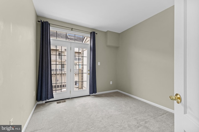 empty room featuring baseboards, visible vents, and light colored carpet