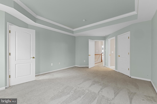 unfurnished bedroom with light carpet, baseboards, a tray ceiling, and crown molding