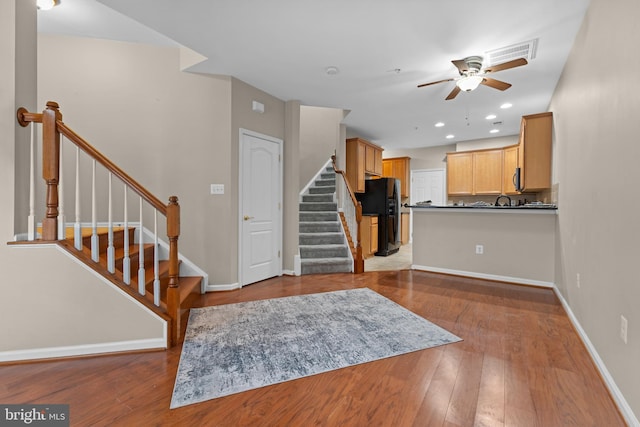 kitchen featuring dark countertops, light wood-style floors, light brown cabinets, and black fridge with ice dispenser